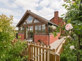 An outdoor view of a house with a patio and flowers at Little Acorn Cottage in Munsley near Ledbury