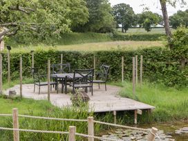 A garden with a wooden deck seating area at Little Acorn Cottage in Munsley near Ledbury