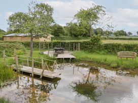 A garden with a pond, bridge, and seating area at Little Acorn Cottage in Munsley near Ledbury