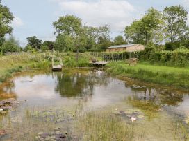 A garden with a pond and seating area at Little Acorn Cottage in Munsley near Ledbury