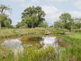 A pond with a bridge and trees at Little Acorn Cottage in Munsley near Ledbury