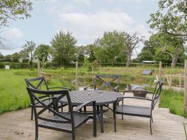 A table with chairs near a pond at Little Acorn Cottage in Munsley near Ledbury