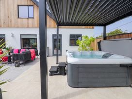 An outdoor patio with a hot tub and seating area at Ardwyn Rhosneigr
