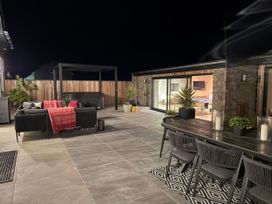 An outdoor area with a hot tub, seating and dining table at Ardwyn Rhosneigr