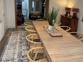 A dining room with wooden table and chairs a patterned rug and a wooden cabinet with lamps at Moss Crag in Glenridding