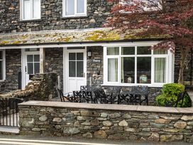 An outdoor seating area with a stone wall and chairs at Moss Crag in Glenridding