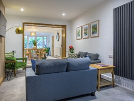 A living room with a sofa, armchair, and dining area at Moss Crag in Glenridding