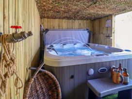 An indoor hot tub with water jets running next to a wooden wall with a hanging rope and a basket at Fishermans Cottage in Prestatyn