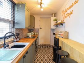 A kitchen with wooden countertops patterned floor tiles and a wall sign reading Fishermans Cottage at Fishermans Cottage in Prestatyn