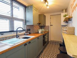 A kitchen with wooden countertops patterned tile flooring and stools at Fishermans Cottage in Prestatyn