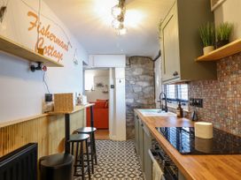 A kitchen with wooden countertop stools and patterned floor tiles at Fishermans Cottage in Prestatyn