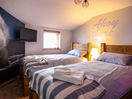 A bedroom with two single beds wooden headboards a lamp and a wall TV at Fishermans Cottage in Prestatyn