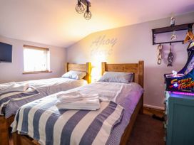 A bedroom with two single beds a lamp a window a wall shelf and a Street Fighter arcade machine at Fishermans Cottage in Prestatyn