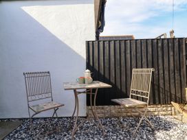 A small outdoor patio with two metal chairs and a table with a teapot and mugs at Fishermans Cottage in Prestatyn
