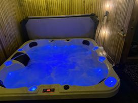 An indoor hot tub with blue lights and water jets in a wooden paneled room at Fishermans Cottage in Prestatyn