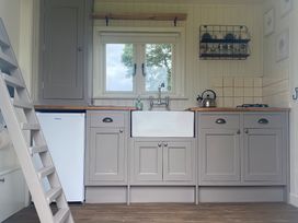 A kitchen with grey cabinets a white sink a small refrigerator a kettle and a ladder at Shepherds Hut 2 Northchapel