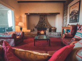 A living room with a fireplace and chairs at Noddfa Country House in Harlech