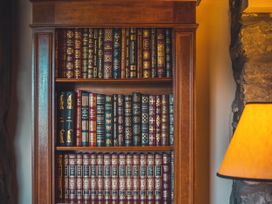 A bookshelf filled with books and a lamp in the library at Noddfa Country House Harlech