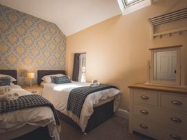 A bedroom with two beds and a dressing table at Noddfa Country House in Harlech