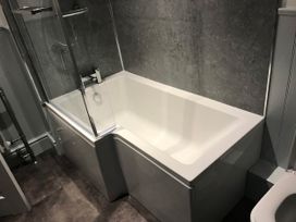 A bathroom with a bathtub and a shower screen at Noddfa Country House in Harlech