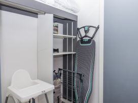 A laundry room with high chair and ironing board at Milana in Tiverton