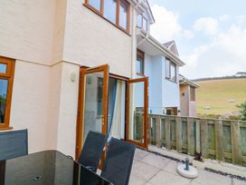 An outdoor area with open doors and furniture at Surf View in Hope Cove
