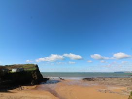A beach and ocean with cliffs and beach huts at Surf View in Hope Cove