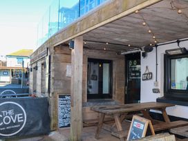 An outdoor bar area with wooden table and signage at The Cove in Hope Cove