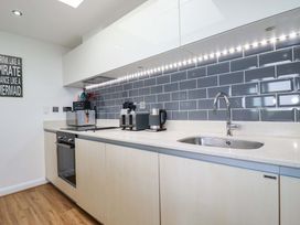A kitchen with stove, sink, coffee maker, and kettle at Penthouse @46Zinc - Headland View in Newquay