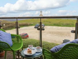 A balcony with chairs and table overlooking a landscape at Penthouse @46Zinc - Headland View, Newquay