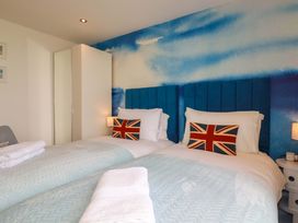 A bedroom with two beds, British flag cushions, and a wardrobe at Penthouse @46Zinc - Headland View, Newquay