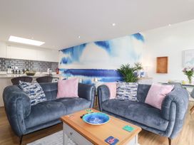 A living room with sofas and a kitchen area at Penthouse @46Zinc - Headland View Newquay