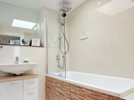 A bathroom with a shower, bathtub, sink, and mirror at Penthouse @46Zinc - Headland View in Newquay