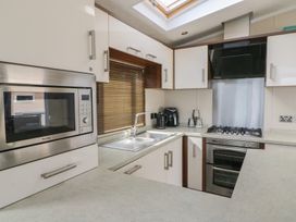 A kitchen with a microwave oven a gas stove a sink and cabinets at Heulwen in New Quay