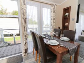 A dining table set with plates glasses and cutlery near sliding glass doors at Heulwen in New Quay