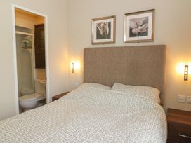 A bedroom with a bed under two framed pictures and an ensuite bathroom visible through an open door at Heulwen in New Quay