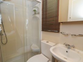 A bathroom with a shower enclosure toilet sink mirror and brown window blinds at Heulwen in New Quay