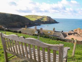 A view from a bench overlooking the sea and hills at 1 The Square Hope Cove