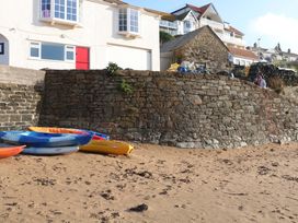 A beach scene with kayaks on sand near a rock wall at 1 The Square Hope Cove