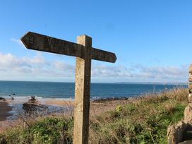 A signpost indicating coast paths to Salcombe and Bantham near the ocean in Hope Cove
