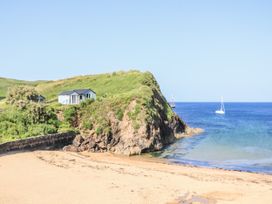 A beach with a house on a cliff near water at 1 The Square Hope Cove