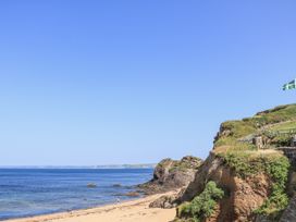 A beach with water and cliffs at 1 The Square in Hope Cove