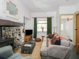 A living room with a stone fireplace a sofa armchair coffee table and television at Cobweb Cottage in Waunfawr