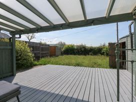 A covered outdoor deck with a garden and fences at Cobweb Cottage in Waunfawr
