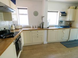 A kitchen with cream cabinets wooden countertops a stove toaster kettle and sink at Annedd Wen in Rhosneigr