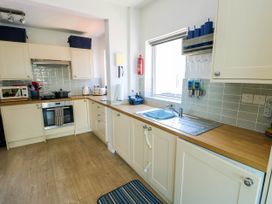 A kitchen with cream cabinets wooden countertops a window and various kitchen appliances at Annedd Wen in Rhosneigr