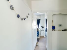 A hallway with nautical heart decorations on the wall leading to a room with a telescope and blue curtains at Annedd Wen in Rhosneigr