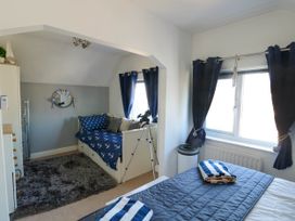 A bedroom with two beds a telescope and windows with dark blue curtains at Annedd Wen in Rhosneigr