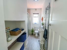 A bathroom with a toilet sink shower shelves and a towel rack at Annedd Wen in Rhosneigr