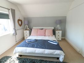 A bedroom with a bed having three pink pillows and two bedside tables with lamps at Annedd Wen in Rhosneigr